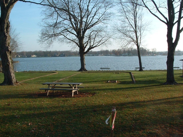 view of home's community with a water view and a lawn