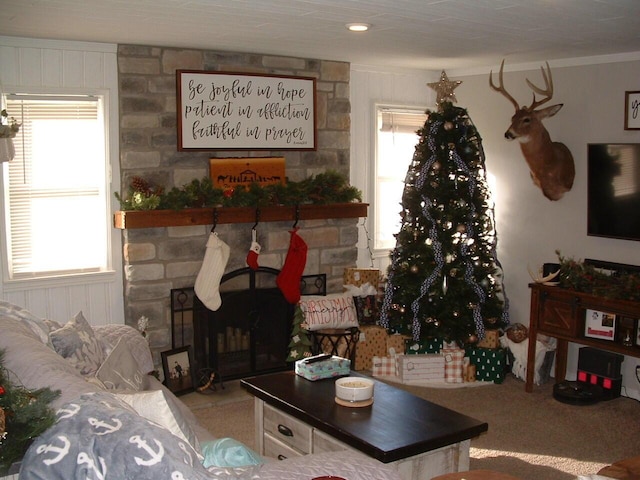 living room featuring a stone fireplace and crown molding