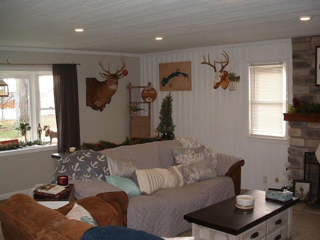 living room with a fireplace, wooden walls, a wealth of natural light, and ornamental molding