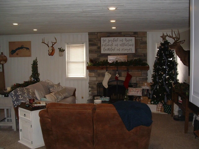 carpeted living room featuring a stone fireplace and wood walls