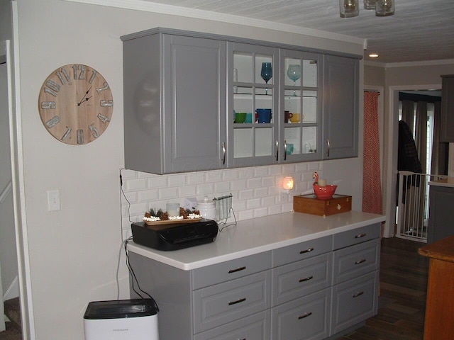 kitchen with gray cabinets, dark hardwood / wood-style flooring, ornamental molding, and backsplash