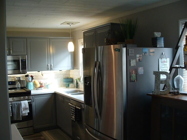 kitchen featuring gray cabinetry, crown molding, pendant lighting, decorative backsplash, and appliances with stainless steel finishes