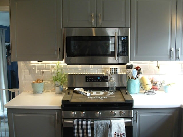 kitchen featuring decorative backsplash, appliances with stainless steel finishes, and gray cabinetry