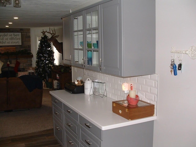 kitchen with tasteful backsplash, gray cabinets, and dark wood-type flooring