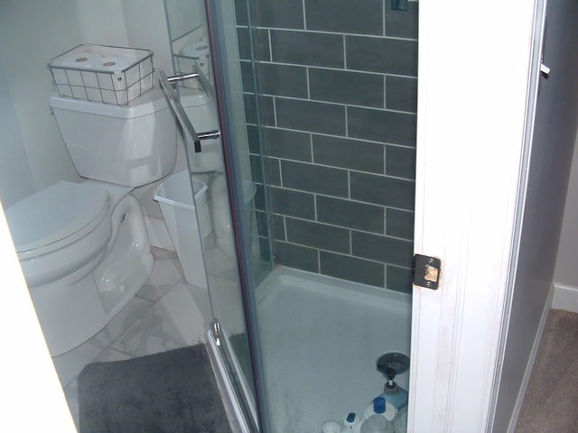 bathroom featuring a tile shower and toilet