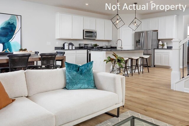 kitchen featuring open floor plan, stainless steel appliances, light wood finished floors, and dark countertops