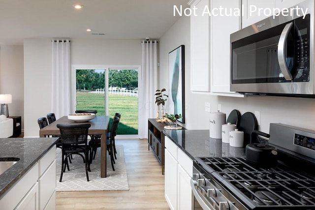 kitchen featuring stainless steel appliances, recessed lighting, white cabinets, light wood-type flooring, and dark stone counters