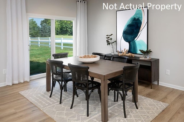 dining space featuring light wood-style flooring and baseboards