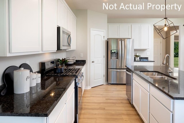 kitchen featuring stainless steel appliances, a sink, white cabinetry, light wood-style floors, and pendant lighting