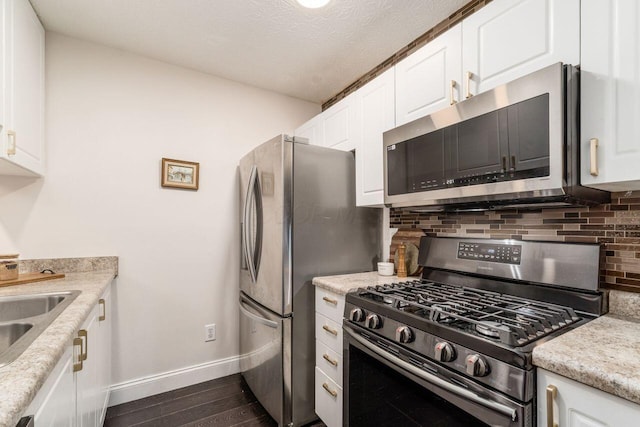 kitchen with white cabinetry, dark wood-type flooring, stainless steel appliances, and a textured ceiling