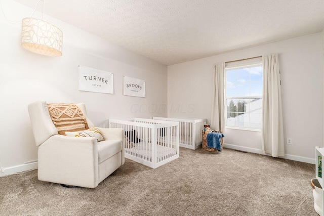 carpeted bedroom with a nursery area and a textured ceiling