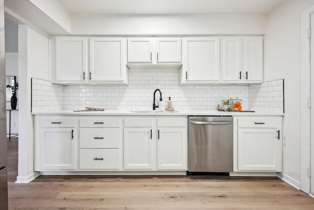 kitchen with sink, stainless steel dishwasher, light wood-type flooring, tasteful backsplash, and white cabinetry