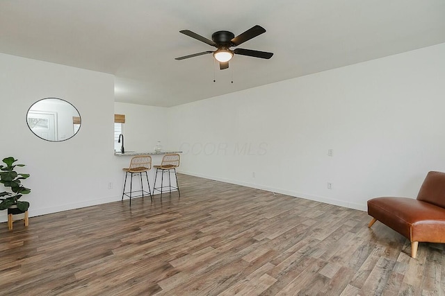 living room with wood-type flooring, ceiling fan, and sink