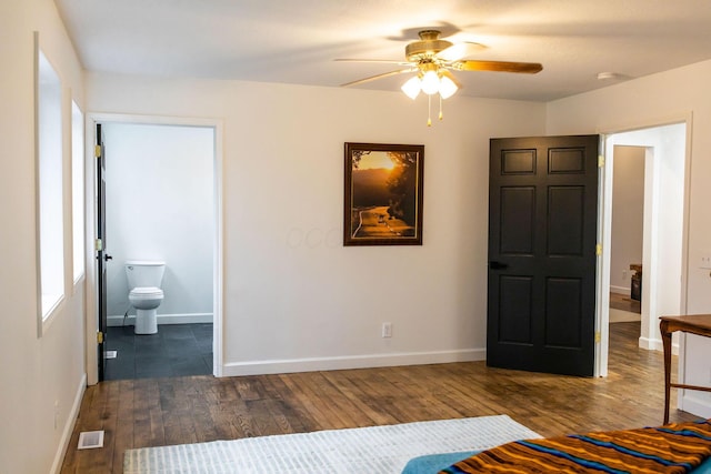 unfurnished bedroom featuring connected bathroom, ceiling fan, and dark wood-type flooring