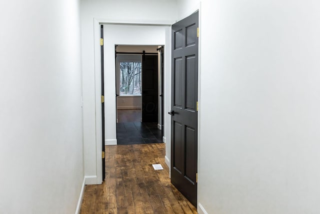 hallway featuring dark hardwood / wood-style floors and a barn door