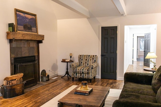 living room with beamed ceiling, dark hardwood / wood-style flooring, and a tiled fireplace