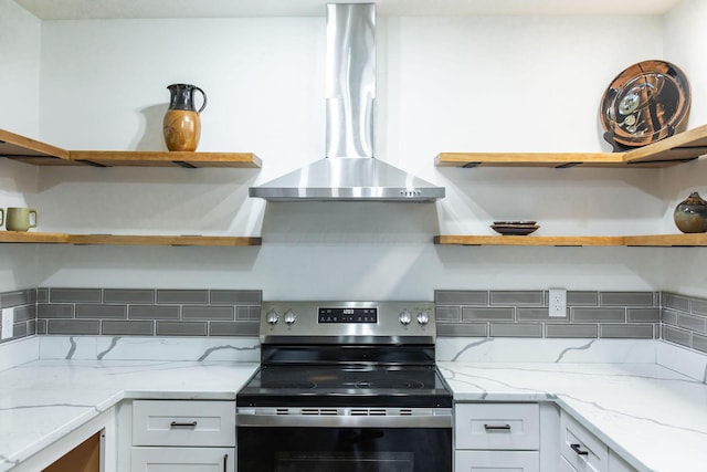 kitchen with wall chimney exhaust hood, electric range, white cabinets, and light stone counters