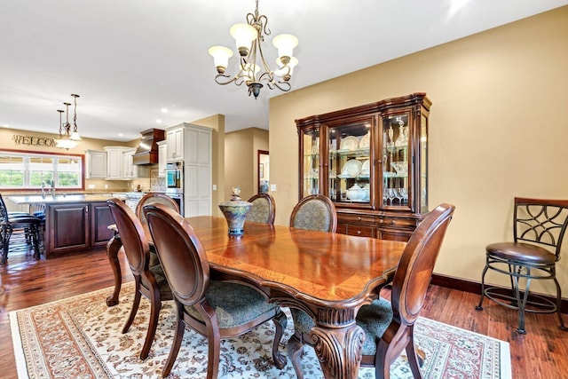 dining area with dark hardwood / wood-style floors and an inviting chandelier