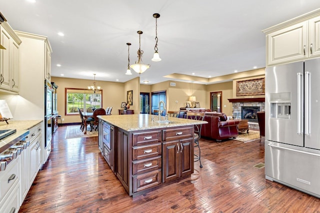 kitchen featuring appliances with stainless steel finishes, a kitchen breakfast bar, decorative light fixtures, a fireplace, and dark hardwood / wood-style floors