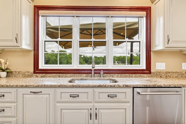 kitchen featuring dishwasher, light stone counters, and plenty of natural light