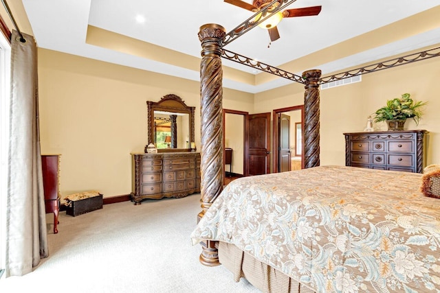 bedroom with a tray ceiling, multiple windows, ceiling fan, and light carpet