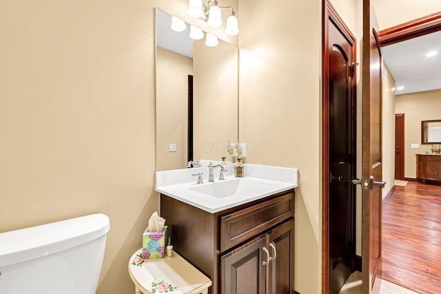 bathroom with hardwood / wood-style floors, vanity, and toilet