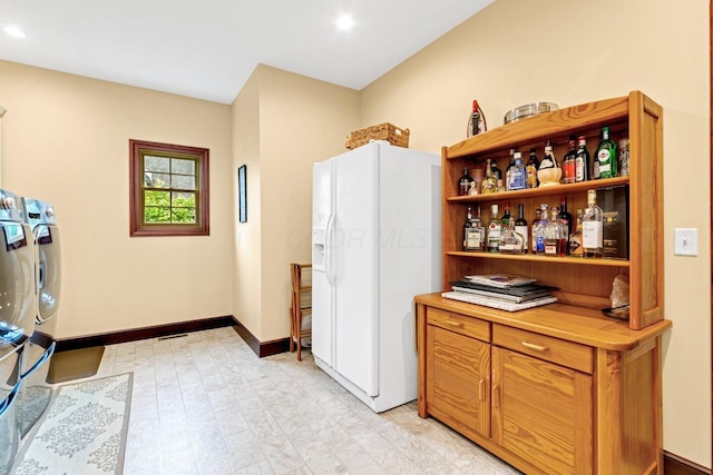 kitchen featuring independent washer and dryer and white fridge with ice dispenser