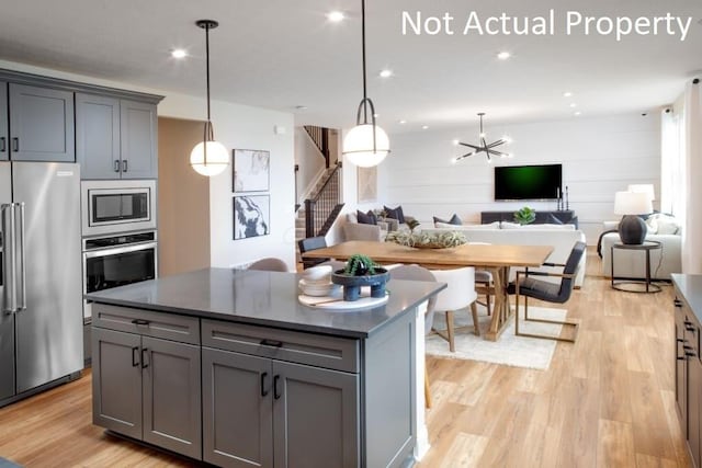 kitchen featuring appliances with stainless steel finishes, gray cabinets, a notable chandelier, and a kitchen island