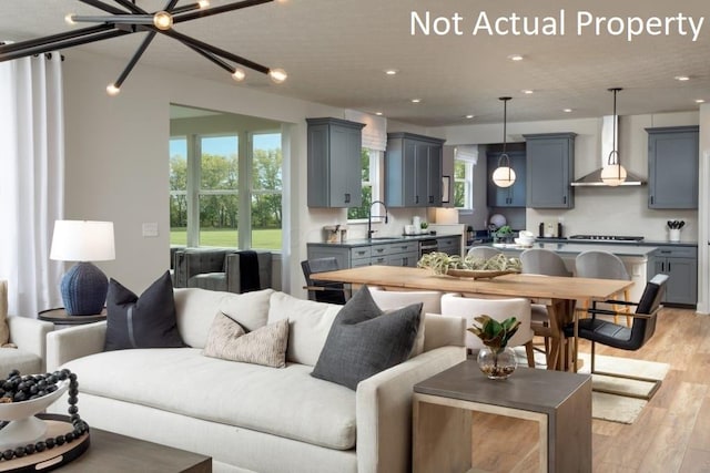 living room featuring a notable chandelier, light hardwood / wood-style flooring, and sink