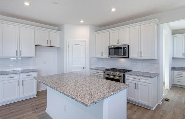 kitchen featuring a center island, white cabinets, stainless steel appliances, and light wood-type flooring