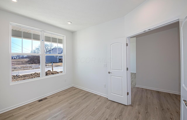 empty room with recessed lighting, baseboards, visible vents, and light wood finished floors