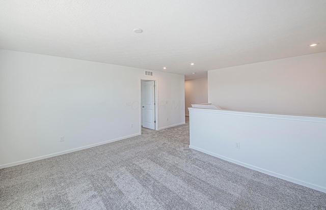 spare room featuring baseboards, visible vents, recessed lighting, a textured ceiling, and light colored carpet