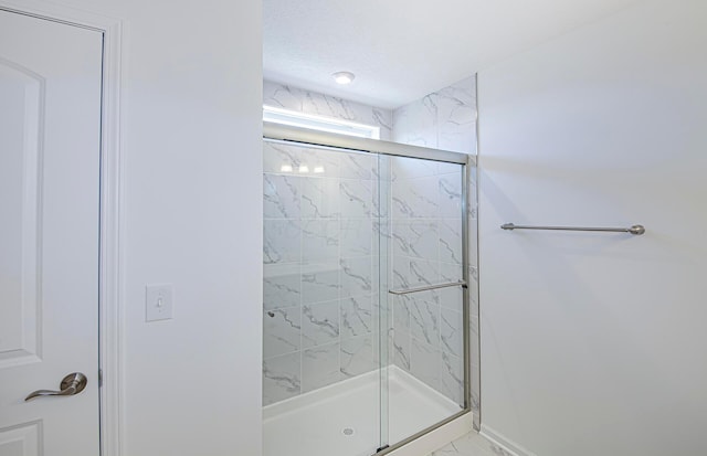 full bathroom with a marble finish shower and a textured ceiling