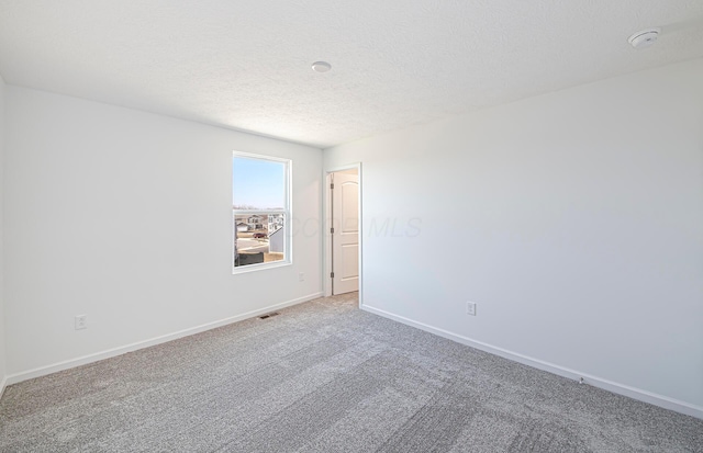 carpeted empty room with baseboards, visible vents, and a textured ceiling