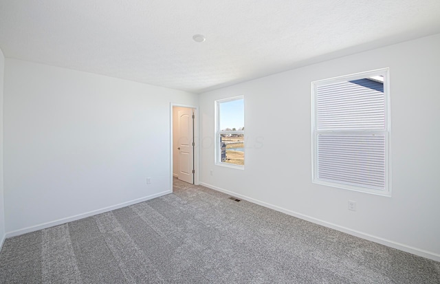 carpeted empty room with visible vents, baseboards, and a textured ceiling