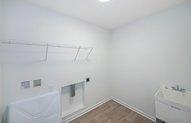 washroom with baseboards, laundry area, hookup for a washing machine, wood finished floors, and a sink