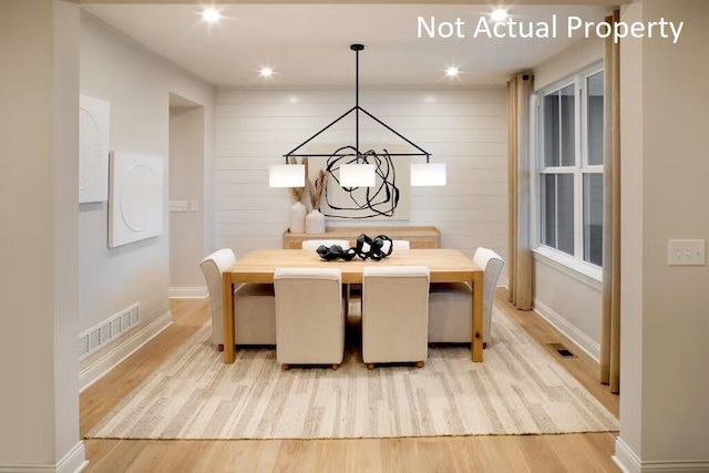 dining space featuring light hardwood / wood-style flooring and wood walls