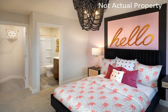 bedroom with carpet floors, connected bathroom, a notable chandelier, and a walk in closet