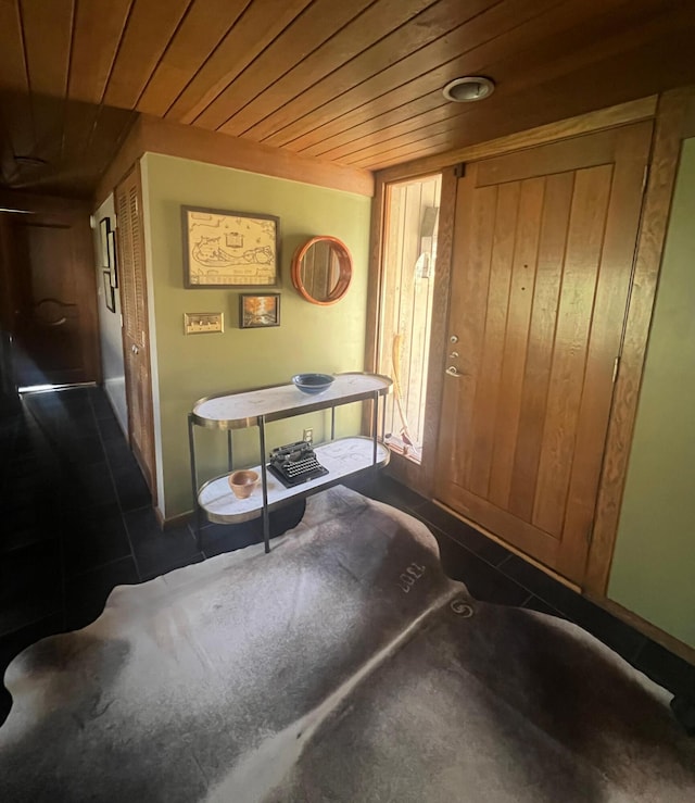 interior space with dark tile patterned floors, wood walls, and wood ceiling