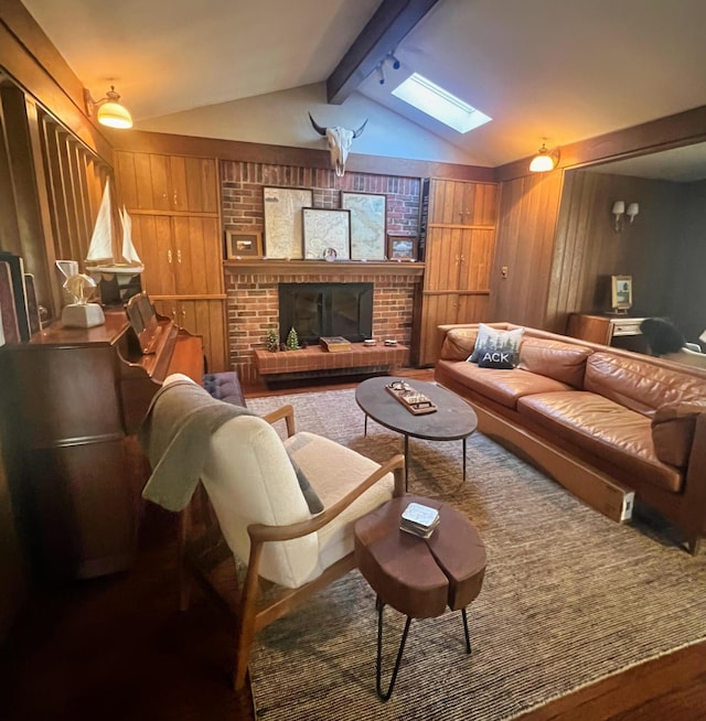 living room featuring wood walls, vaulted ceiling with skylight, and a brick fireplace