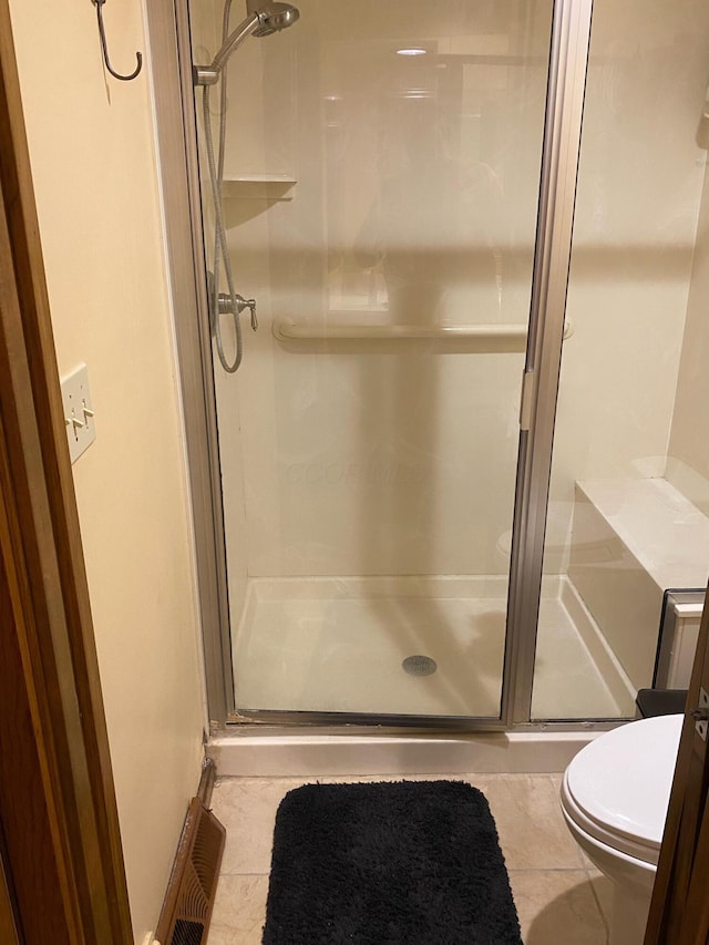 bathroom with tile patterned flooring, a shower with shower door, and toilet