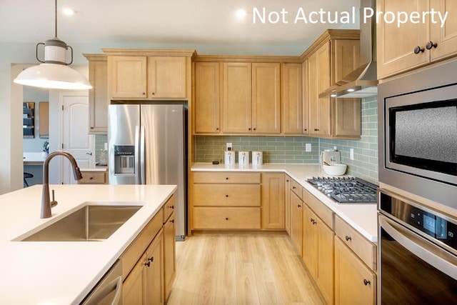 kitchen featuring appliances with stainless steel finishes, wall chimney range hood, sink, backsplash, and hanging light fixtures