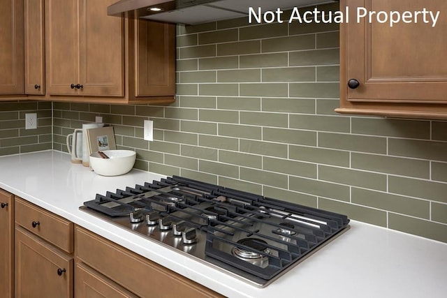 kitchen featuring decorative backsplash, exhaust hood, and black gas stovetop