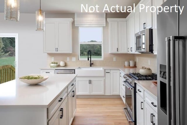 kitchen with white cabinets, light wood-type flooring, sink, and high end appliances