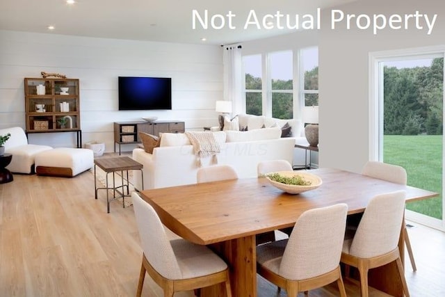 dining space with light hardwood / wood-style floors and wooden walls