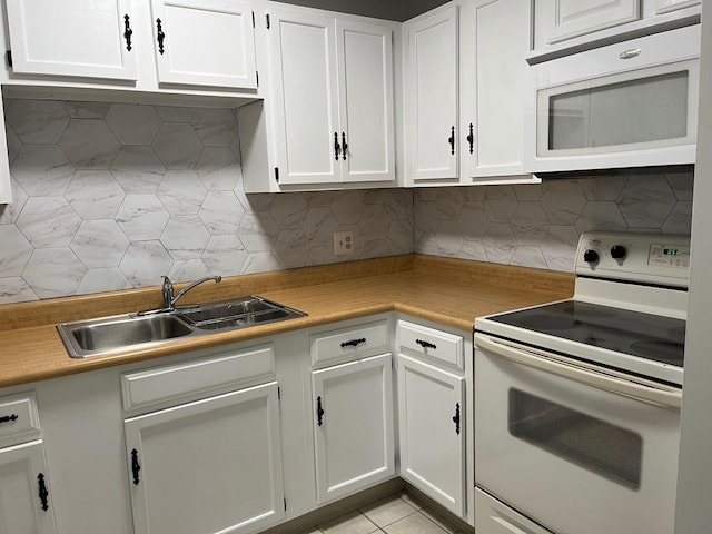 kitchen with decorative backsplash, white appliances, sink, white cabinetry, and light tile patterned flooring