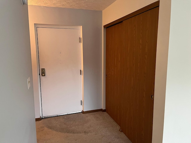 hall featuring a textured ceiling and light colored carpet