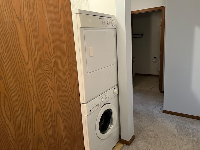 washroom with stacked washer / drying machine and light colored carpet