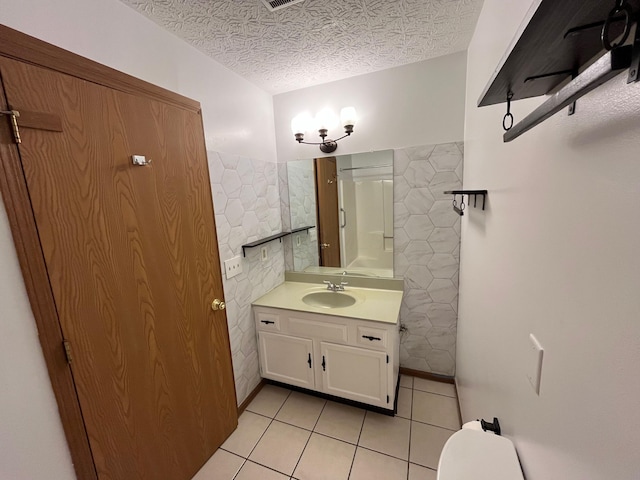 bathroom featuring a textured ceiling, tile patterned flooring, vanity, and tile walls