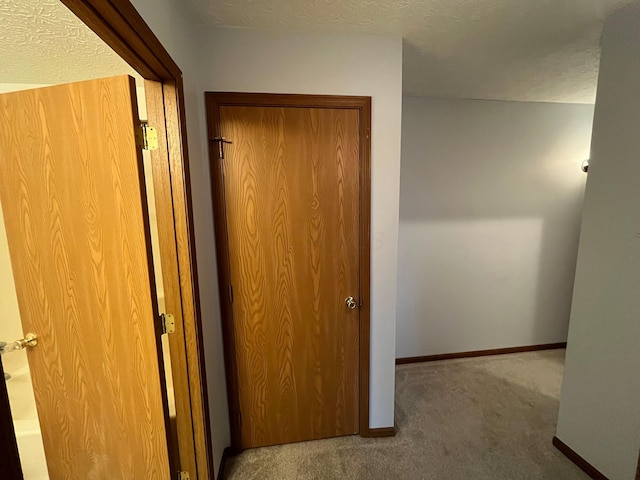 hallway with carpet floors and a textured ceiling